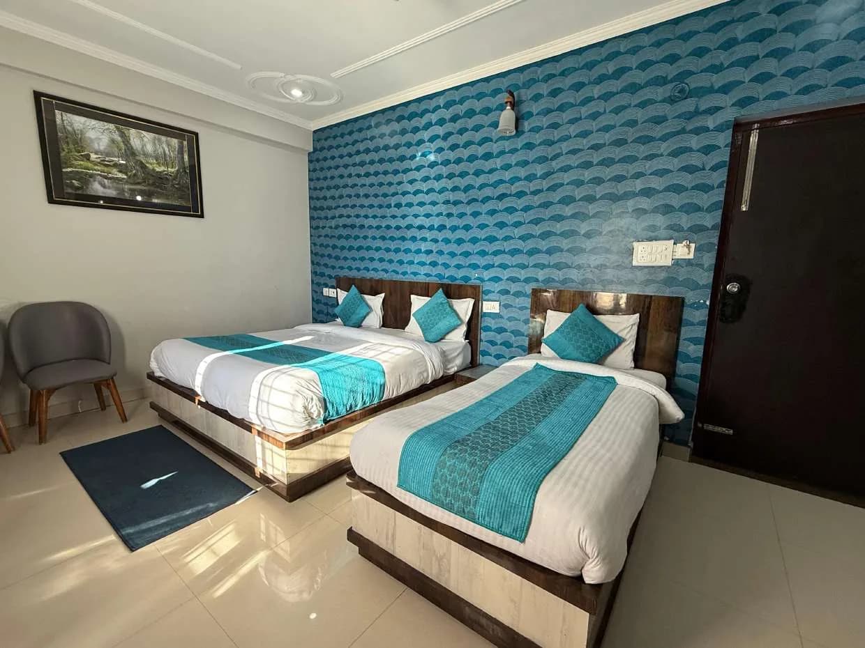 Room with a larger and a smaller bed against a blue wave-pattern wall