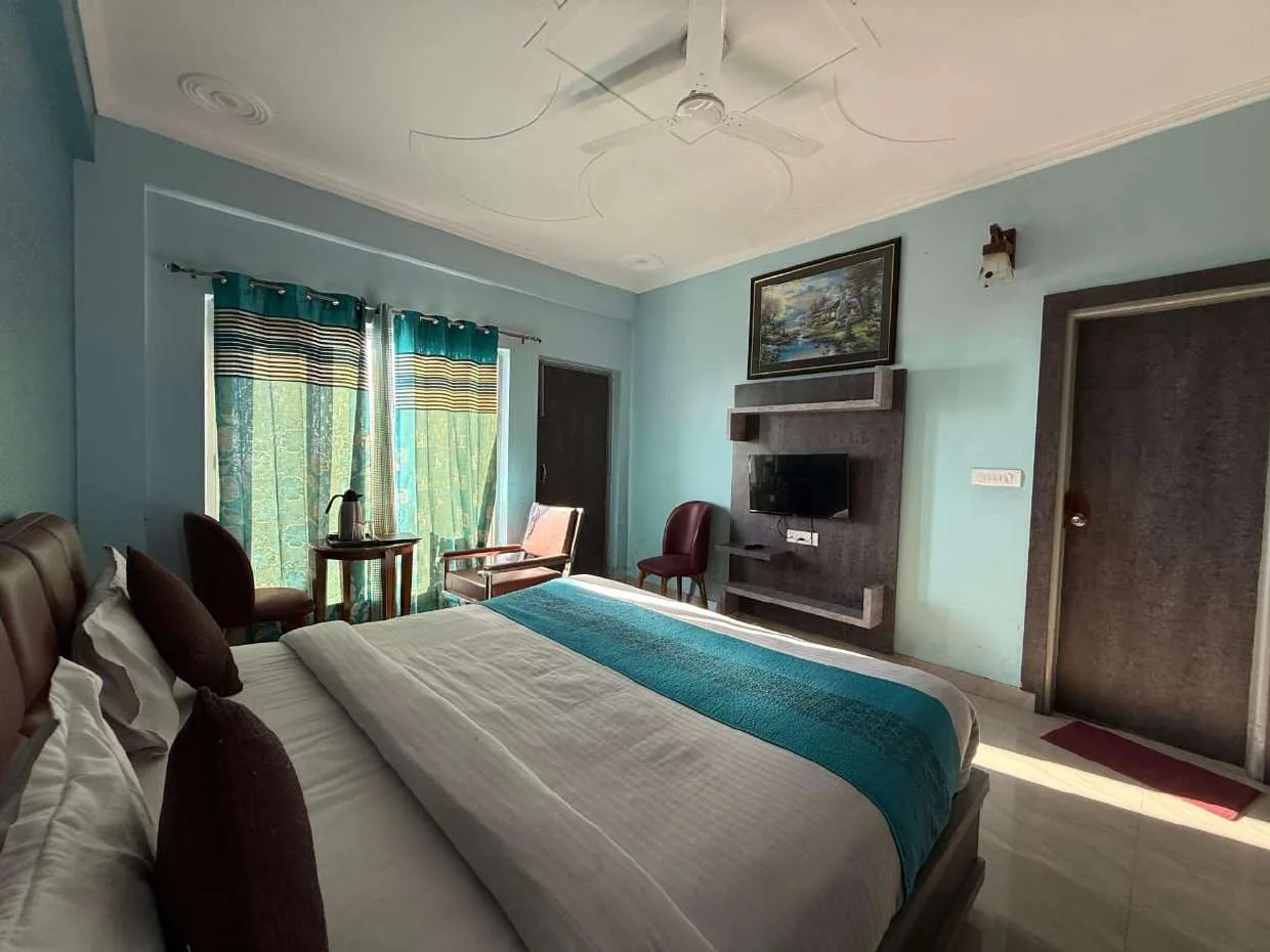 Light-blue room with double bed, wall-mounted TV and framed painting